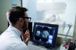 Male radiologist reviewing at brain MRI scan results in control room.