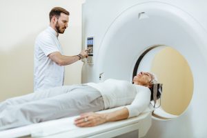 Medical technician starting MRI scan procedure of mature patient